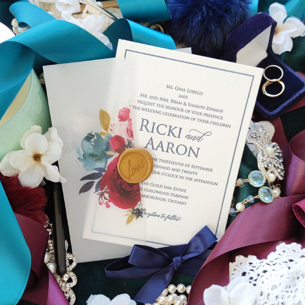 A letterpress wedding invitation with navy ink wrapped in floral printed vellum paper.