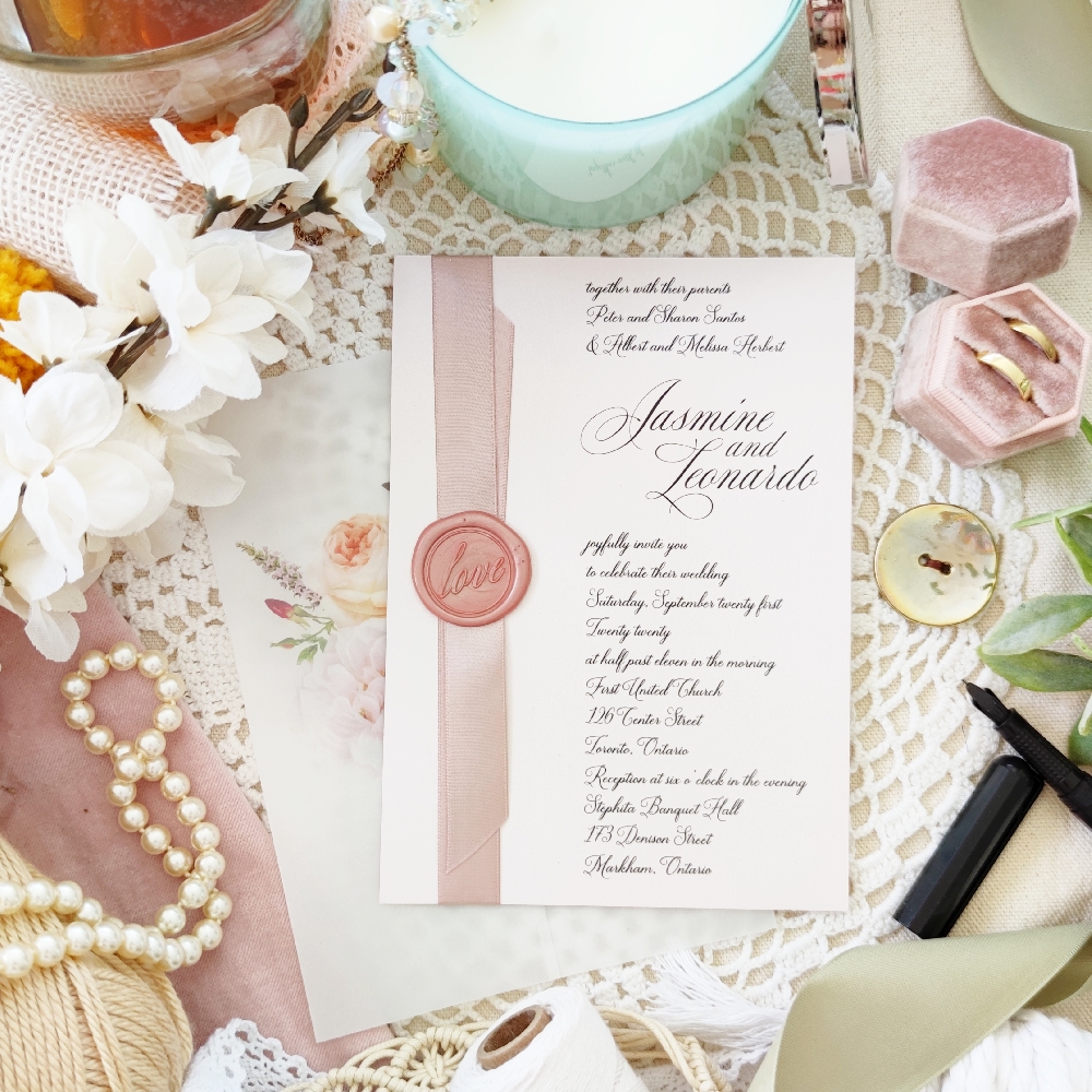 An invitation with pink on pink tones from the wedding invitation card to the ribbon and wax seal.