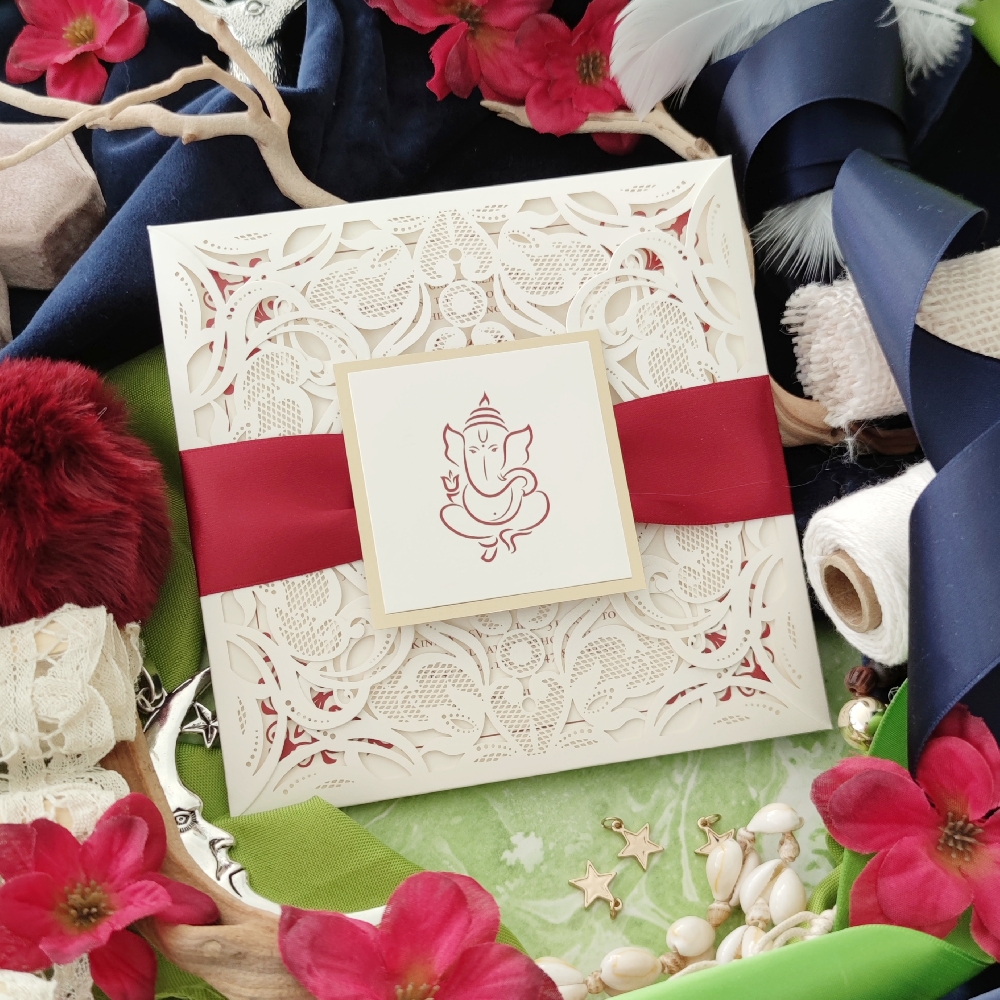 Ivory lasercut invite design with deep sherry ribbon and Ganesha printed on front cover.