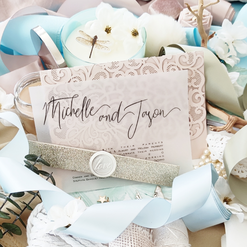 Wedding invitation wording printed on 5x7 vellum paper with a champagne glitter paper wrapped into a belly band and fastened with a wax seal.