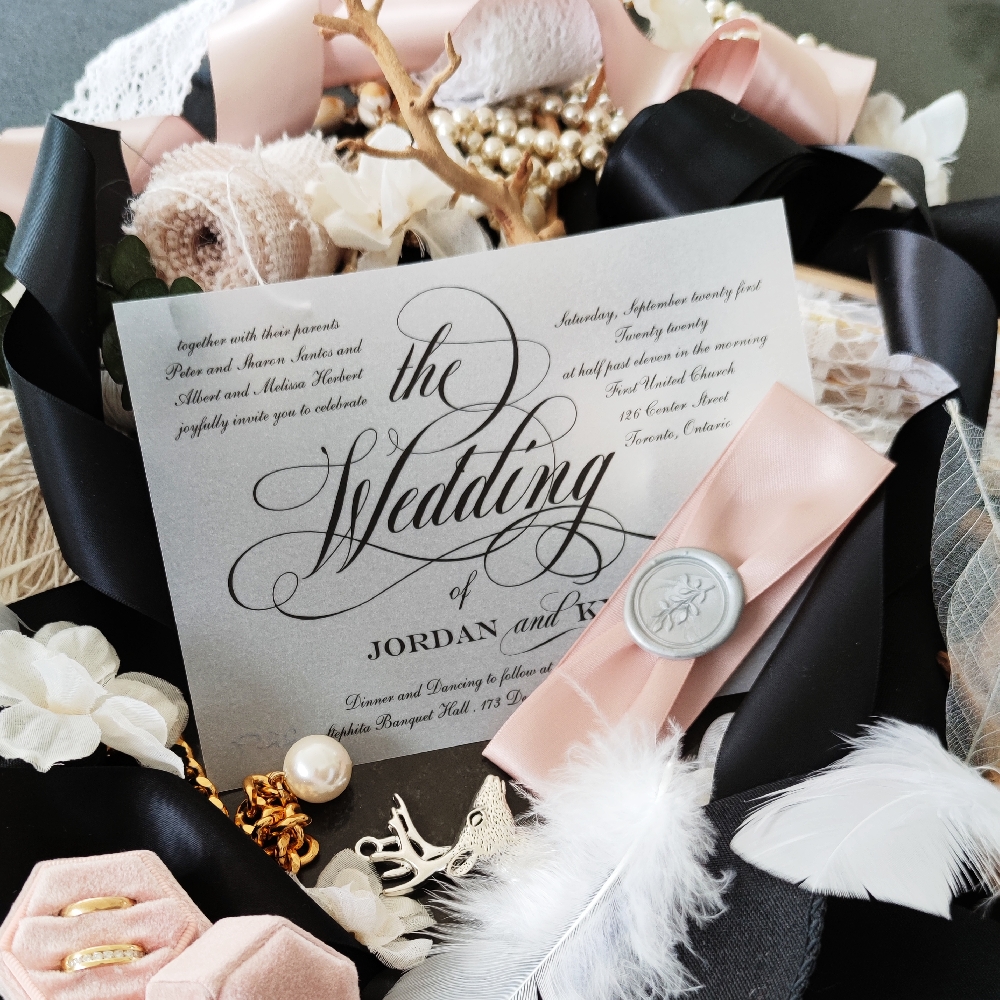 Simple wedding invitation printed on rice paper also known as vellum and wrapped with a thick dark blush ribbon and silver wax seal.