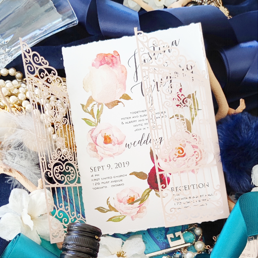 There are essentially two invitation designs in this photo.  The invitation wording is printed on a deckled paper and a blush garden gate lasercut is wrapped around the invitation card.