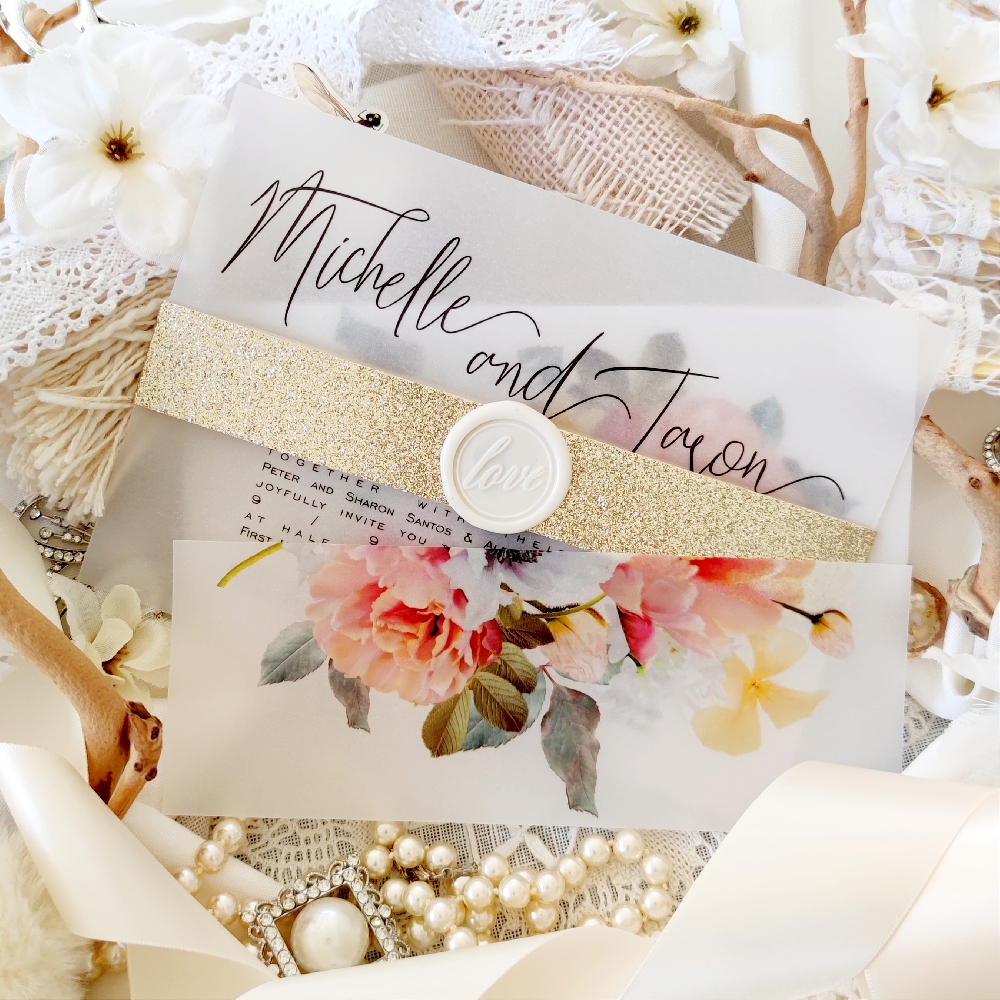 A vellum wedding invitation with a champagne gold glitter bellyband around the card, and finished with an ivory wax seal.