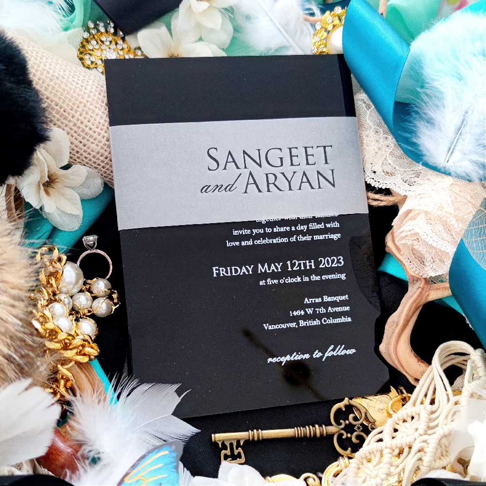 Sangeet & Aryan decided on a Black Acrylic Wedding Invite with a vellum belly band.  White ink screen printing was used on the acrylic.
