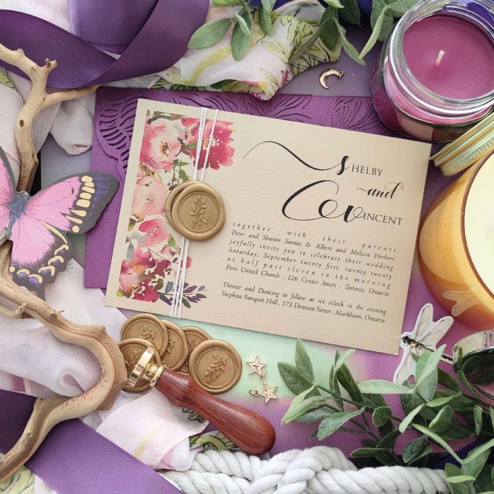 A landscape direction wedding invitation with a string tied around the card and a wax seal over the string.