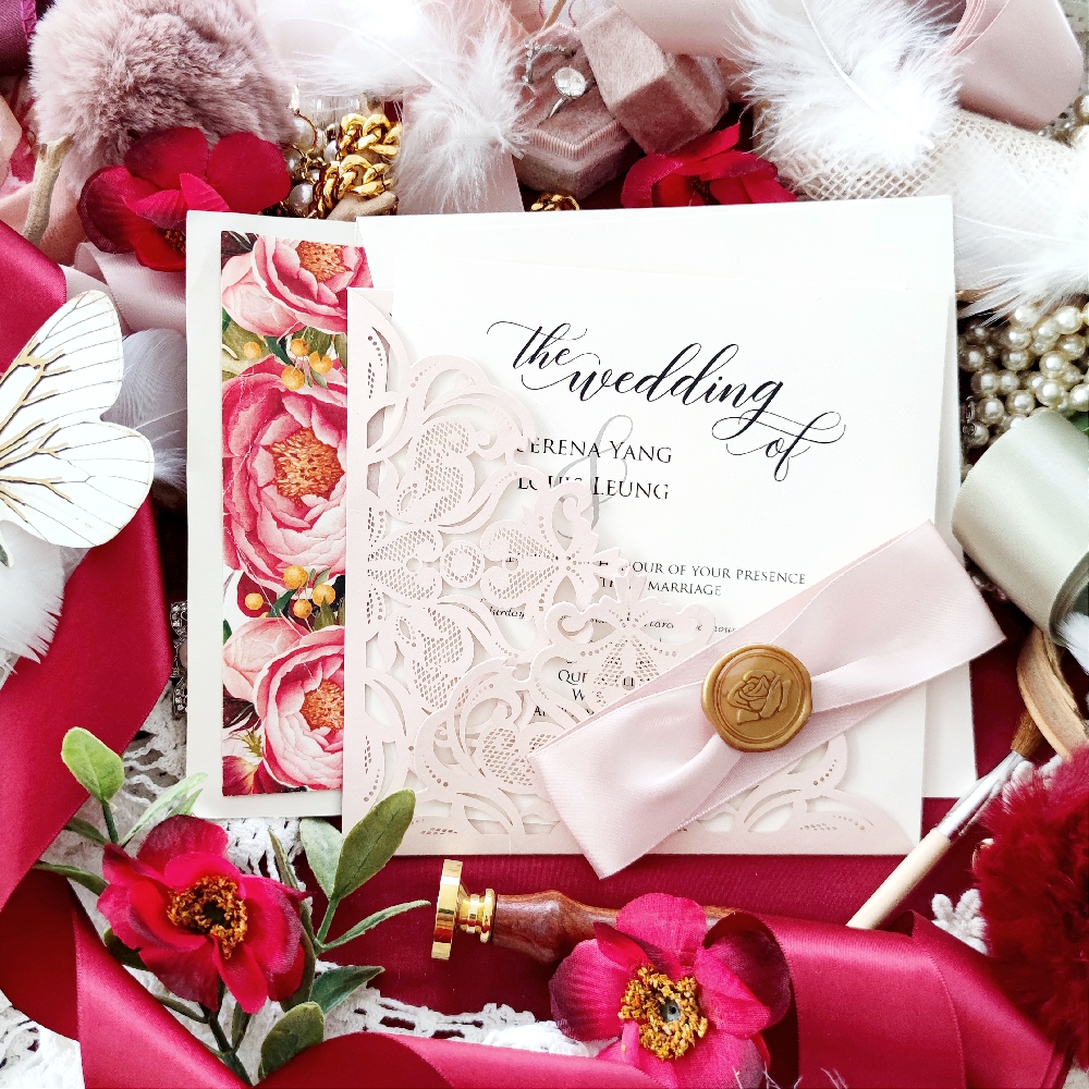 This is a custom wedding invitation that uses a blush shimmer laser cut folder.  It is embellished with a pink satin ribbon and gold wax seal.  The envelopes are lined with a custom floral graphic.