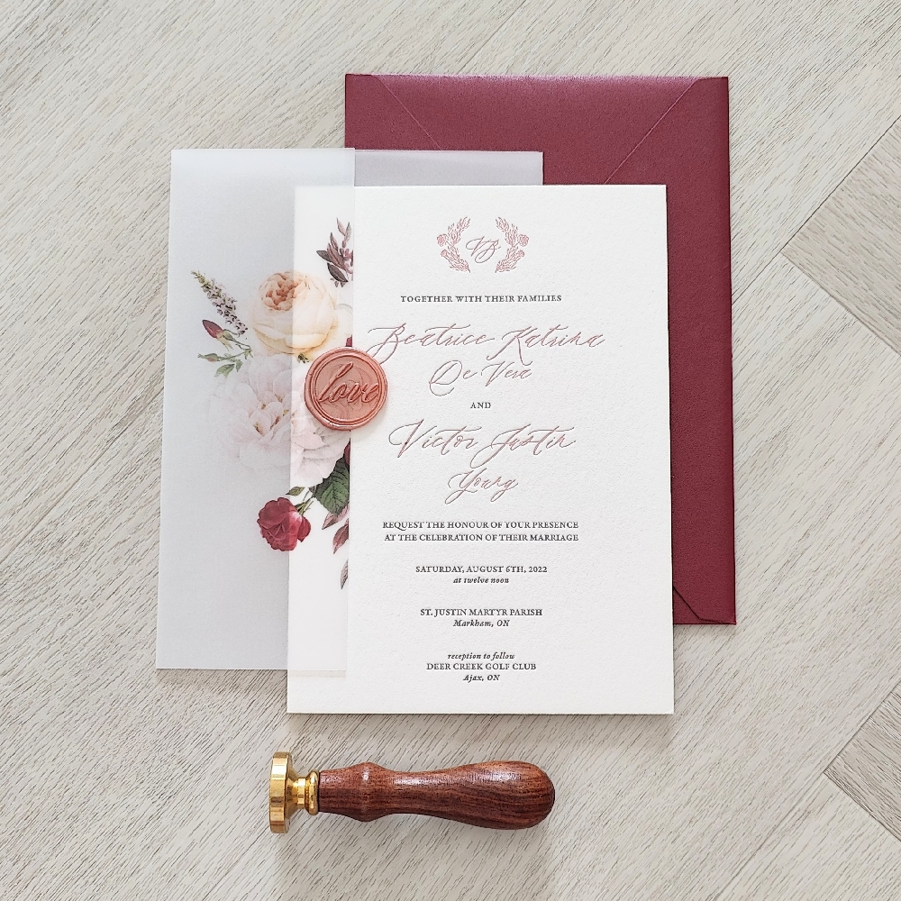 Letterpress wedding invite with a full vellum wrap with gold wax seal and floral print embellishments.