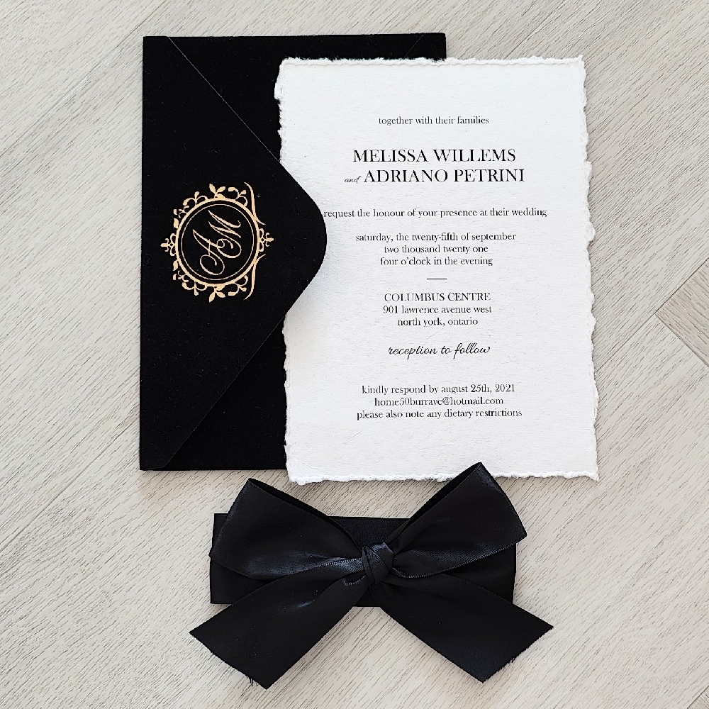Deckle edge wedding invite on white cotton with a black bow and black velvet envelope.