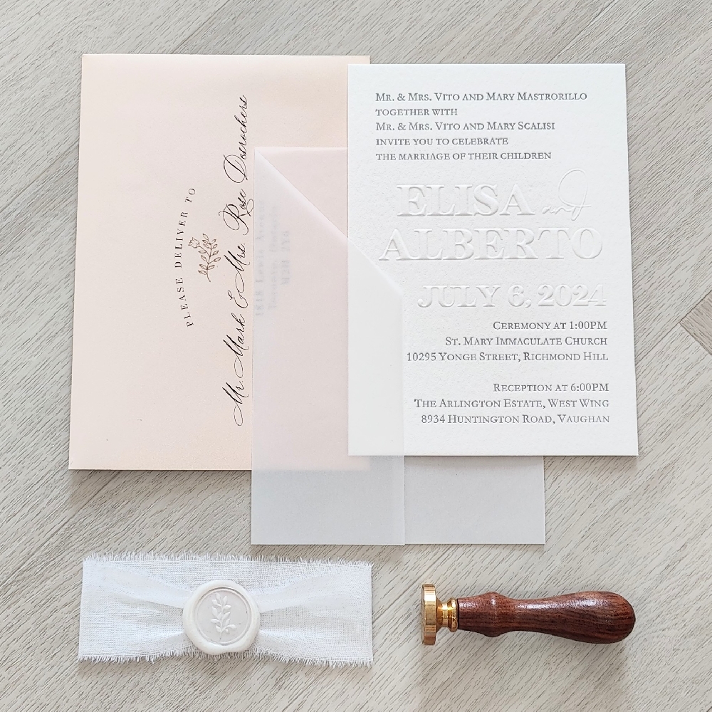Blind embossed invitation with a vellum wrap and lace and wax seal embellishment.  Blush envelope.