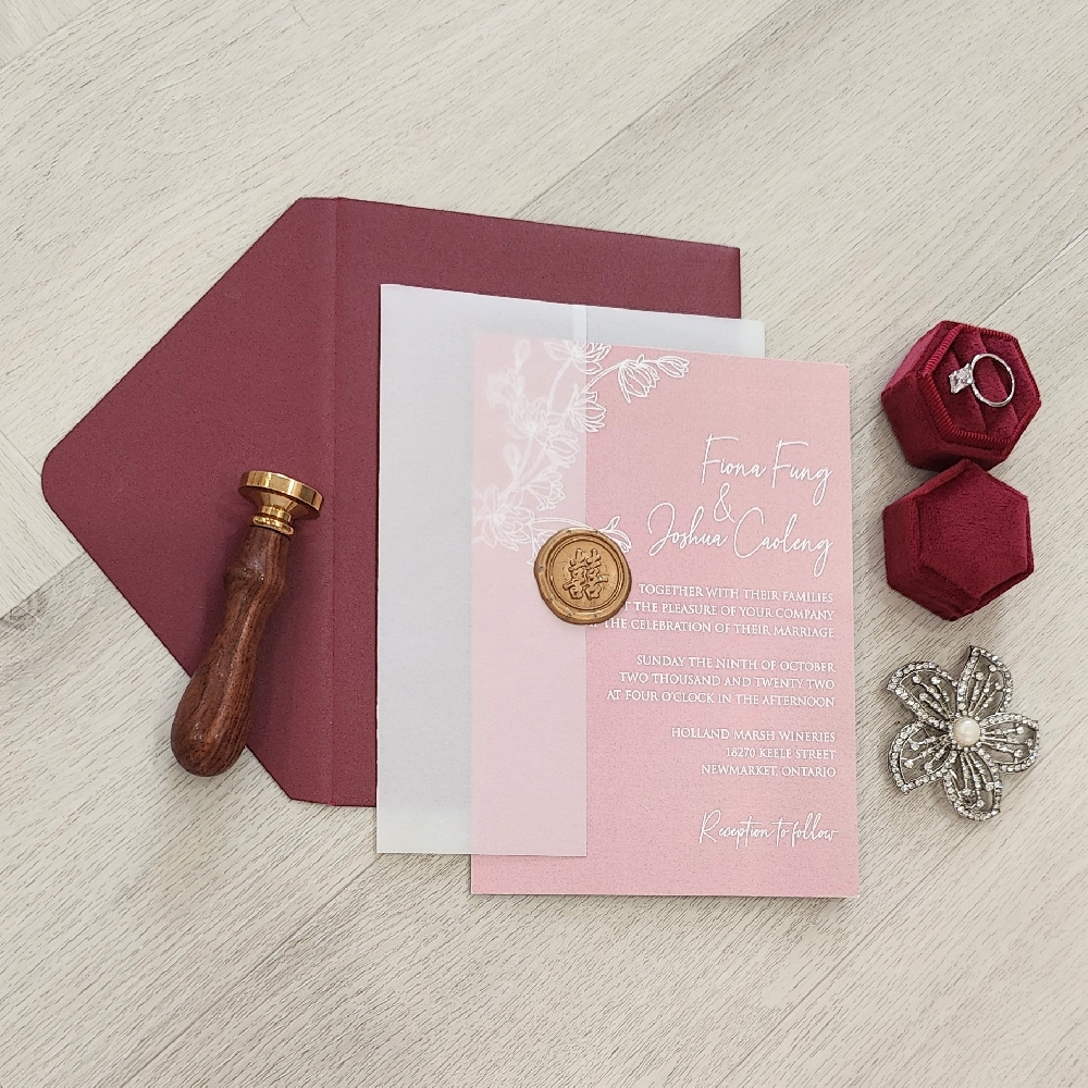 Single card invitation with a full blush color background print along with a clear vellum wrap and gold wax seal embellishment.  This goes into a burgundy shimmer envelope.