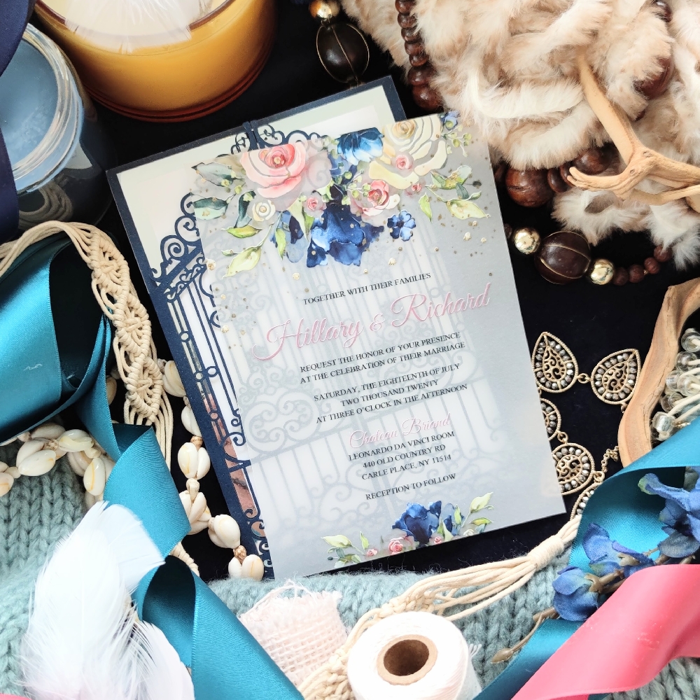 A 5x7 vellum wedding invitation with pink and royal blue florals and pink names.