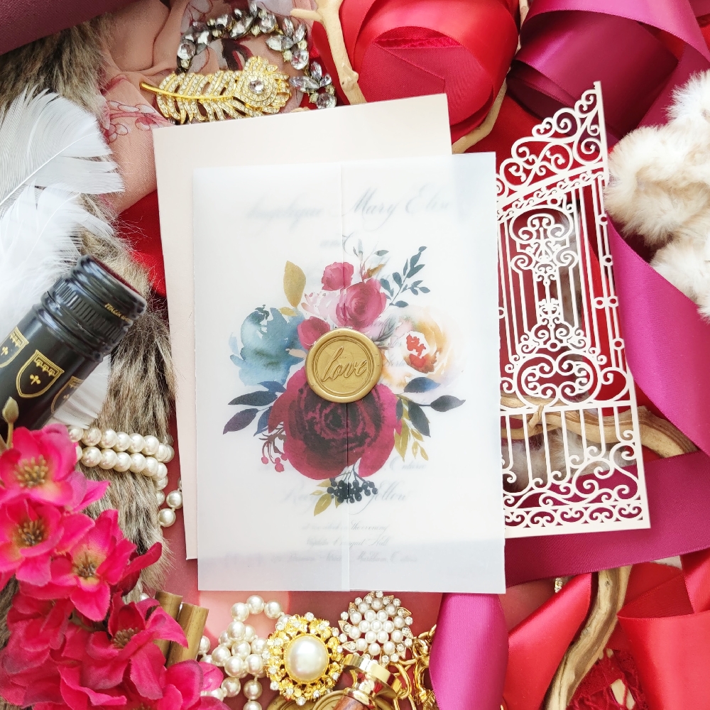 A  vellum gatefold wedding invitation with floral pattern and gold love wax seal.