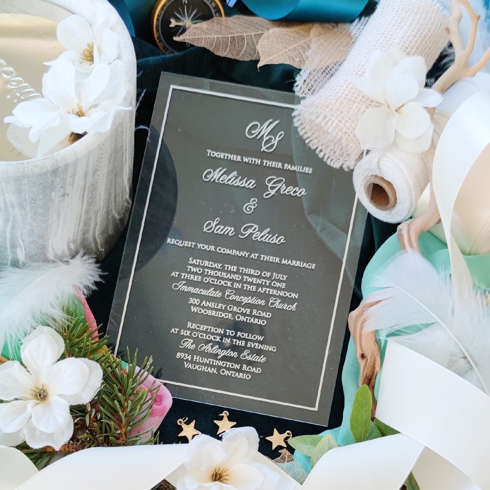 Clear acrylic wedding invitation with monogram printed at the top.