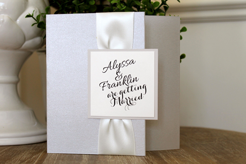 Invitation 1547: Silver Ore, Stone, Cream Smooth, Antique Ribbon - This popular square pocketfold uses silver pearl paper and an antique ribbon pinched in the middle with a square tag.