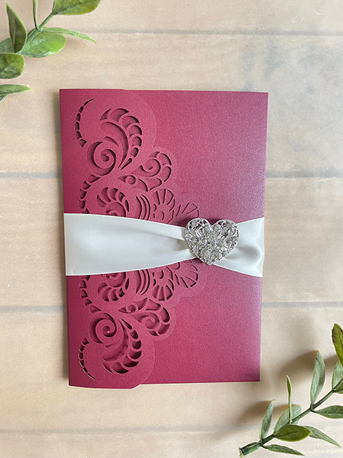 Invitation lc157: Burgundy Shimmer, Antique Ribbon, Brooch/Buckle U - This is a burgundy shimmer colored lasercut with a 1.5 inch pinched ribbon tied around the card and finished with a rhinestone brooch.