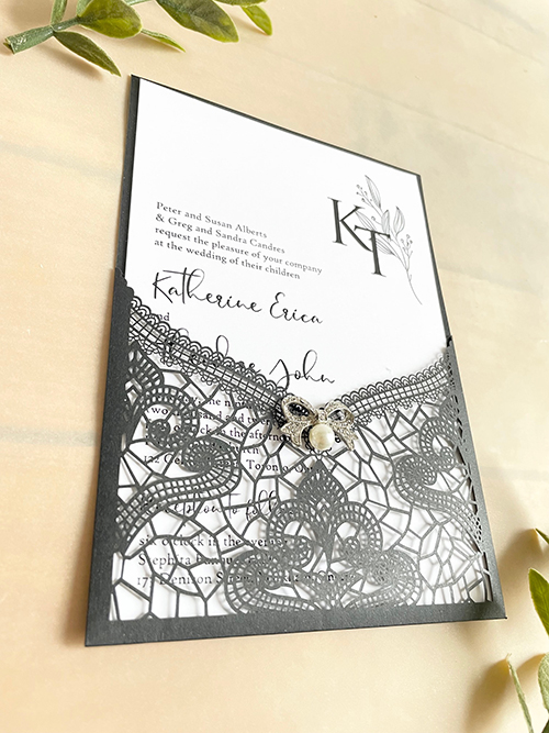 Invitation lc161:  - This is a delicate black lasercut wedding invitation.  The bow brooch on the front adds a soft touch to the black lace design.